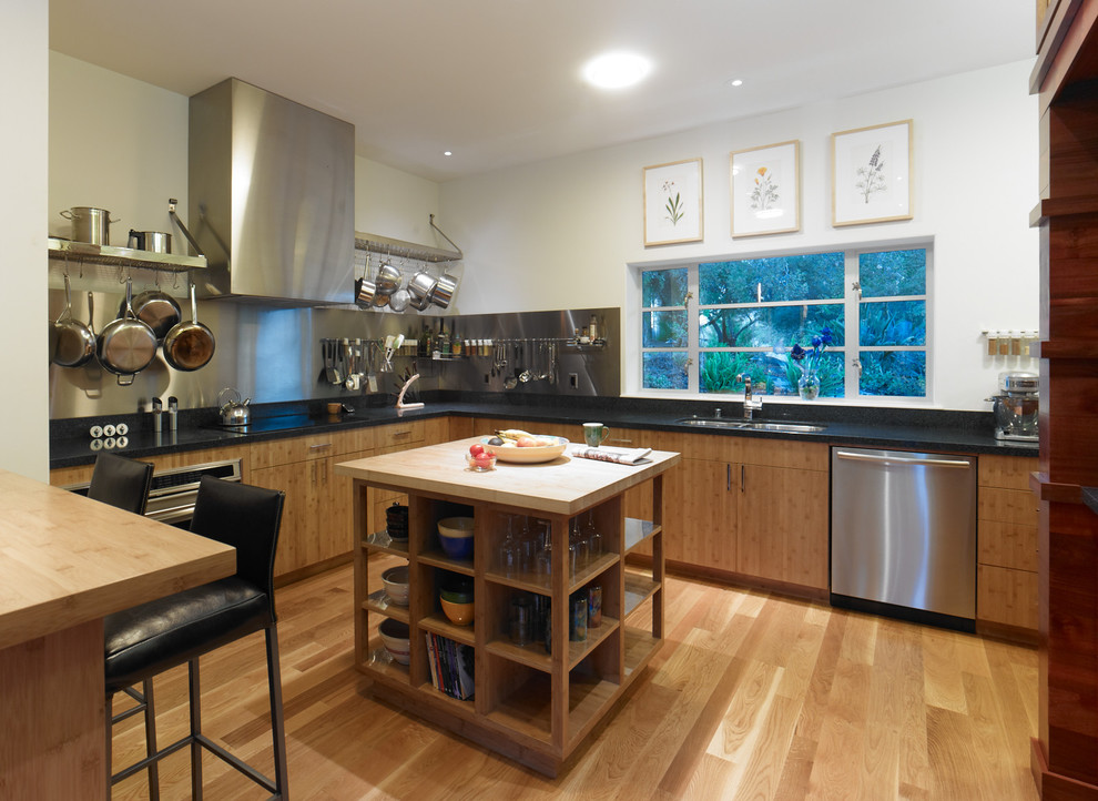 На фото: угловая кухня в современном стиле с обеденным столом, двойной мойкой, плоскими фасадами, фасадами цвета дерева среднего тона, фартуком цвета металлик и техникой из нержавеющей стали