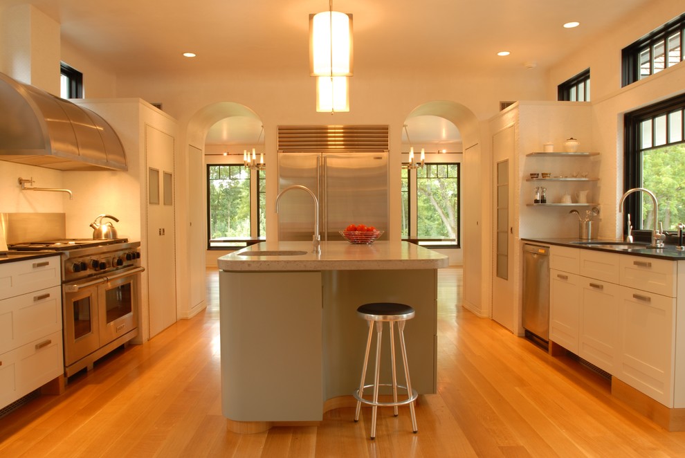 Idéer för ett stort modernt u-kök, med rostfria vitvaror, luckor med infälld panel, vita skåp, vitt stänkskydd, stänkskydd i tunnelbanekakel, en undermonterad diskho, ljust trägolv, en köksö och beiget golv