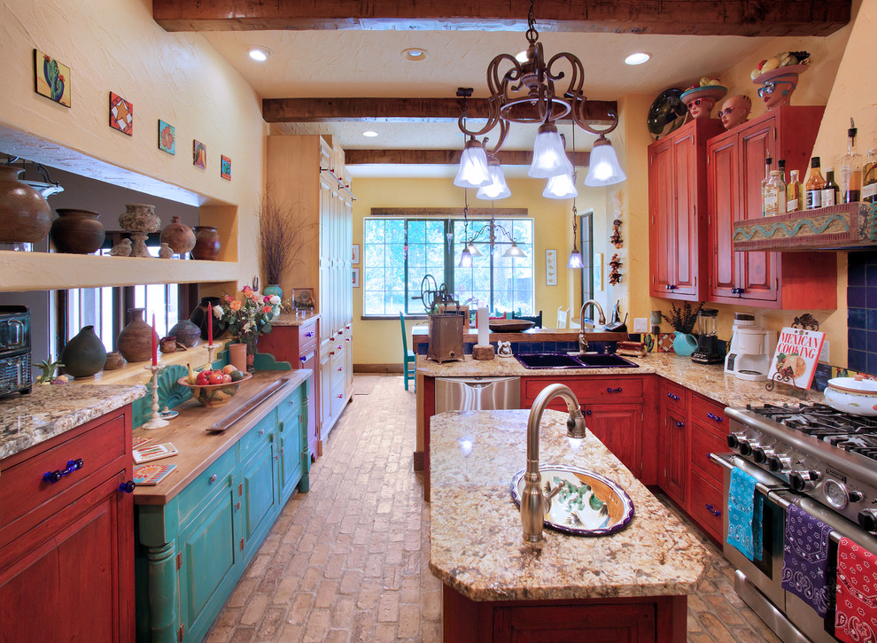 Cette image montre une cuisine sud-ouest américain avec des portes de placard rouges, un évier posé, un placard avec porte à panneau surélevé et un électroménager en acier inoxydable.