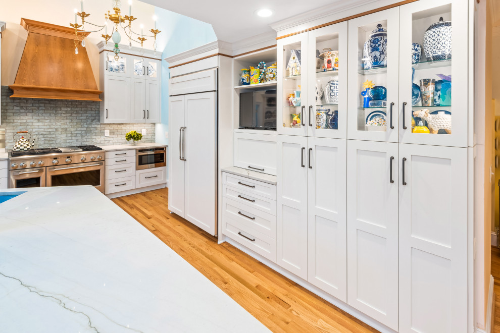 Foto di una cucina classica con lavello sottopiano, ante in stile shaker, ante bianche, paraspruzzi grigio, elettrodomestici da incasso, pavimento in legno massello medio, pavimento marrone e top bianco