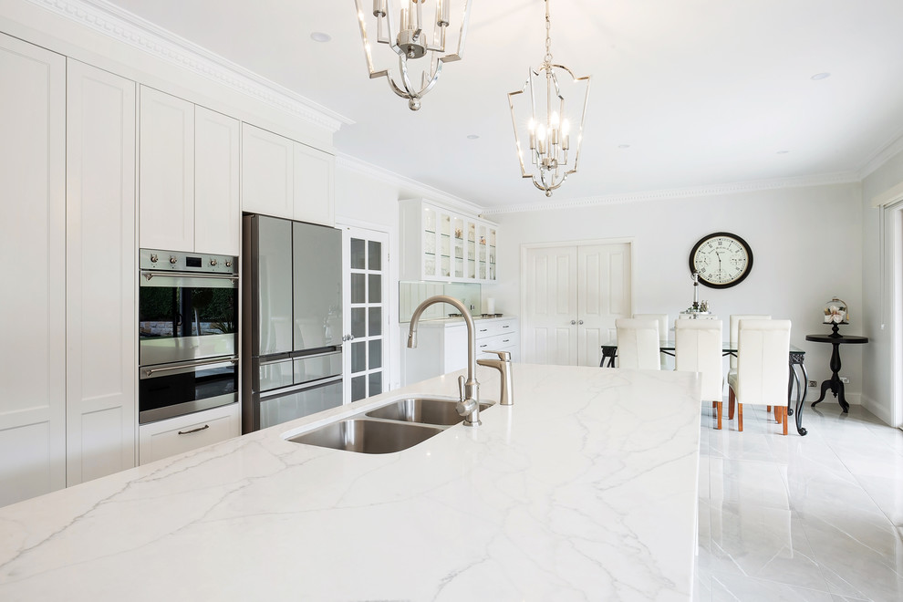 Example of a large classic l-shaped porcelain tile and brown floor open concept kitchen design in Sydney with an undermount sink, shaker cabinets, beige cabinets, quartz countertops, gray backsplash, stone slab backsplash, stainless steel appliances, an island and white countertops