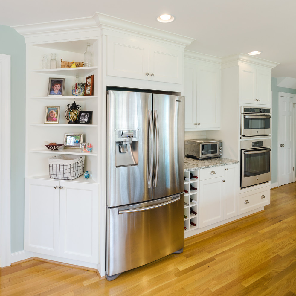 Idée de décoration pour une cuisine tradition avec un évier de ferme, un placard avec porte à panneau encastré, des portes de placard noires, un plan de travail en quartz, une crédence bleue, un électroménager en acier inoxydable, un sol en bois brun et îlot.