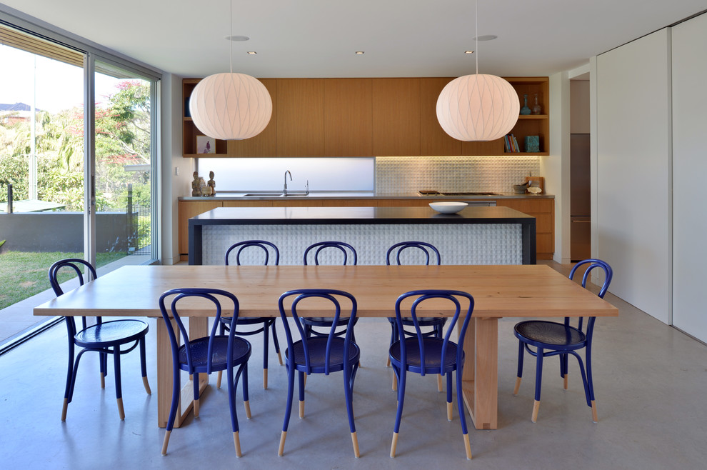 Пример оригинального дизайна: кухня в современном стиле с обеденным столом, двойной мойкой, плоскими фасадами, светлыми деревянными фасадами, фартуком цвета металлик, бетонным полом, островом и окном