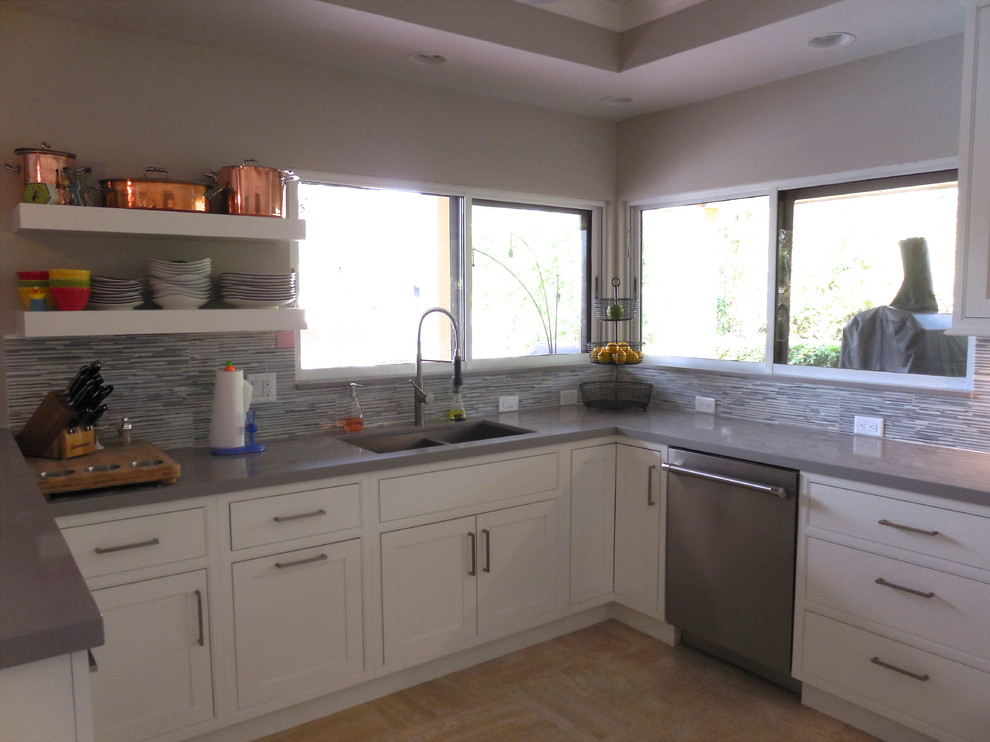Bild på ett vintage kök och matrum, med en undermonterad diskho, luckor med profilerade fronter, vita skåp, bänkskiva i kvarts, grått stänkskydd och rostfria vitvaror