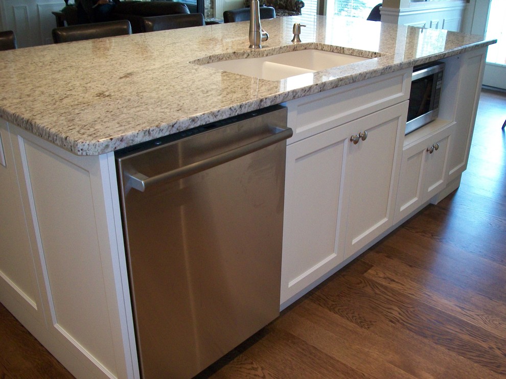 Klassisk inredning av ett mellanstort kök, med en undermonterad diskho, skåp i shakerstil, vita skåp, granitbänkskiva, beige stänkskydd, stänkskydd i stenkakel, rostfria vitvaror, mellanmörkt trägolv och en köksö