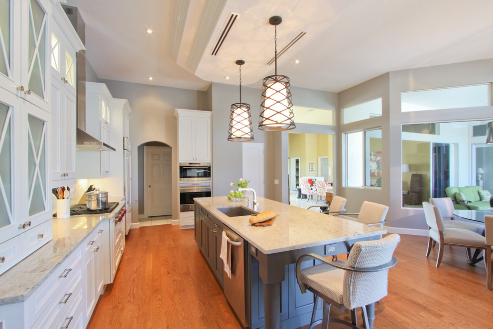 Exempel på ett modernt kök, med en undermonterad diskho, skåp i shakerstil, vita skåp, granitbänkskiva, vitt stänkskydd, stänkskydd i tunnelbanekakel, rostfria vitvaror, mellanmörkt trägolv, en köksö och brunt golv
