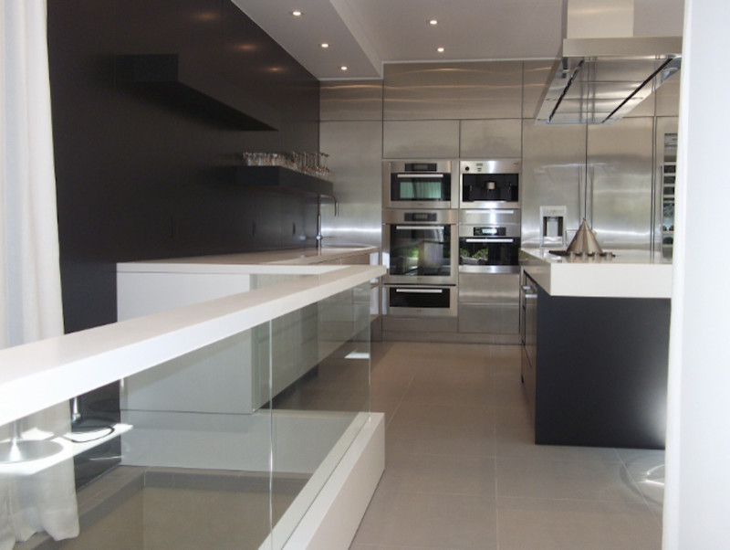 Bild på ett stort funkis kök, med en enkel diskho, släta luckor, vita skåp, bänkskiva i koppar, svart stänkskydd, rostfria vitvaror, klinkergolv i porslin och flera köksöar