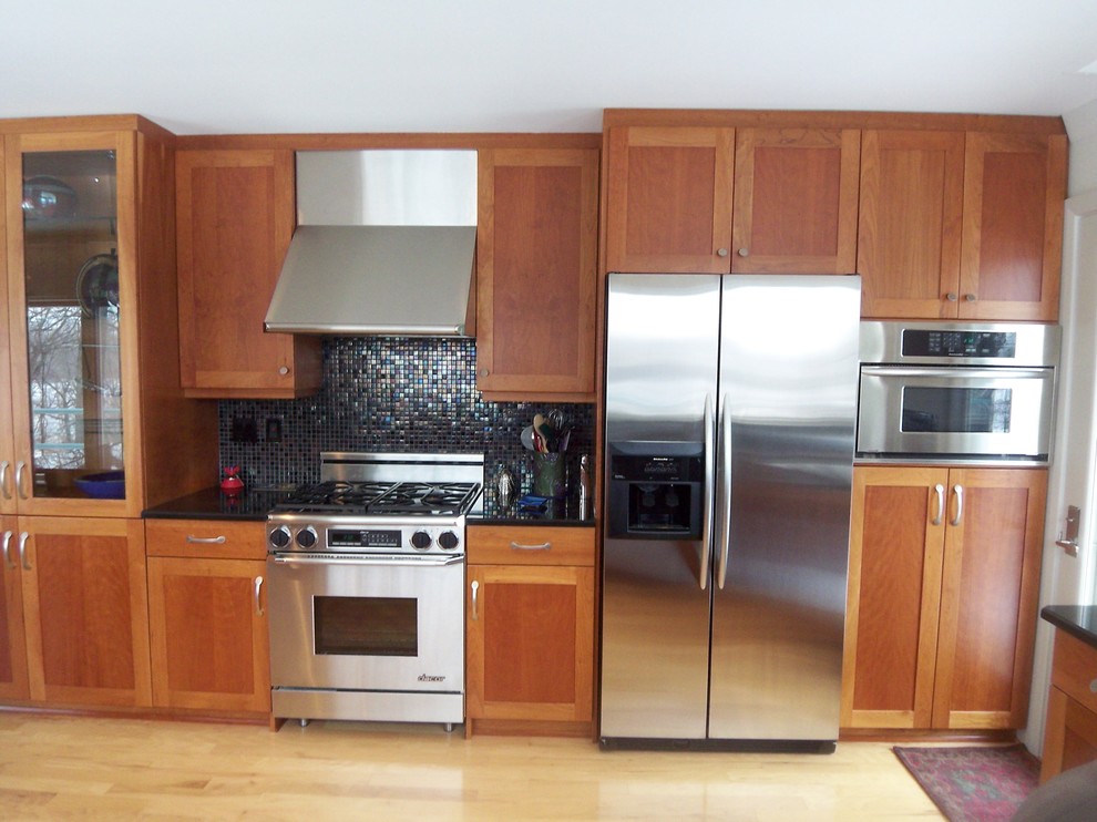 Foto på ett mellanstort funkis kök, med en undermonterad diskho, skåp i shakerstil, skåp i mellenmörkt trä, granitbänkskiva, flerfärgad stänkskydd, stänkskydd i mosaik, rostfria vitvaror, klinkergolv i porslin och en halv köksö