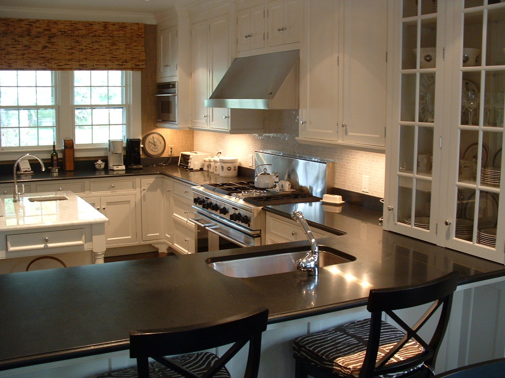 Exemple d'une cuisine américaine chic avec un placard à porte plane, des portes de placard blanches, une crédence en céramique, un électroménager en acier inoxydable et îlot.