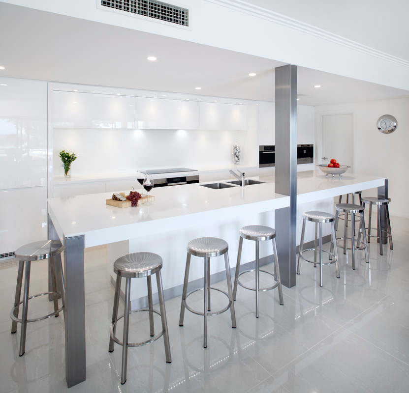 Inspiration for a large contemporary l-shaped eat-in kitchen remodel in Sydney with a drop-in sink, flat-panel cabinets, white cabinets, quartz countertops, white backsplash, stone slab backsplash, stainless steel appliances and an island