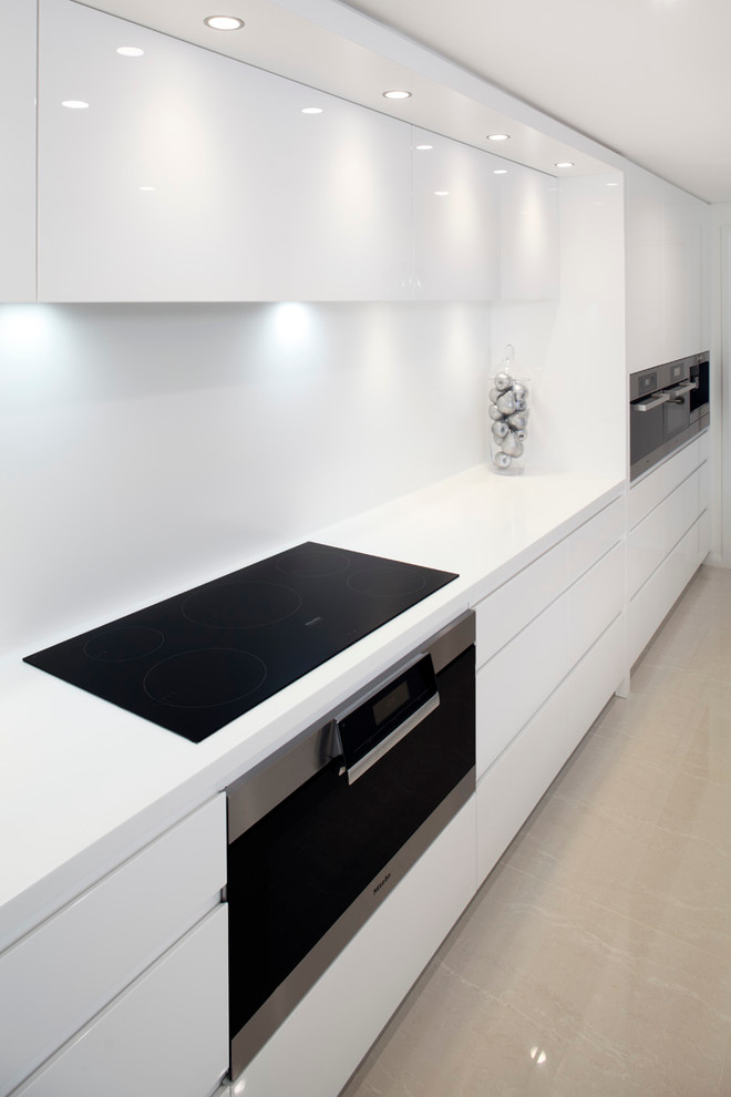 Eat-in kitchen - large contemporary l-shaped eat-in kitchen idea in Sydney with a drop-in sink, flat-panel cabinets, white cabinets, quartz countertops, white backsplash, stone slab backsplash, stainless steel appliances and an island