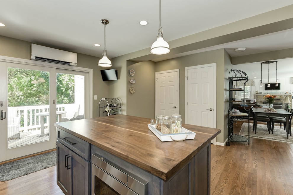 Exempel på ett avskilt, mellanstort klassiskt l-kök, med en undermonterad diskho, skåp i shakerstil, skåp i mörkt trä, bänkskiva i täljsten, beige stänkskydd, stänkskydd i stenkakel, rostfria vitvaror, ljust trägolv, en köksö och brunt golv