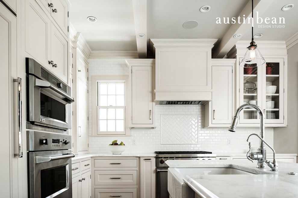 Klassische Küche mit Landhausspüle, Glasfronten, weißen Schränken, Marmor-Arbeitsplatte, Küchenrückwand in Weiß, Rückwand aus Metrofliesen, Küchengeräten aus Edelstahl und braunem Holzboden in Sonstige