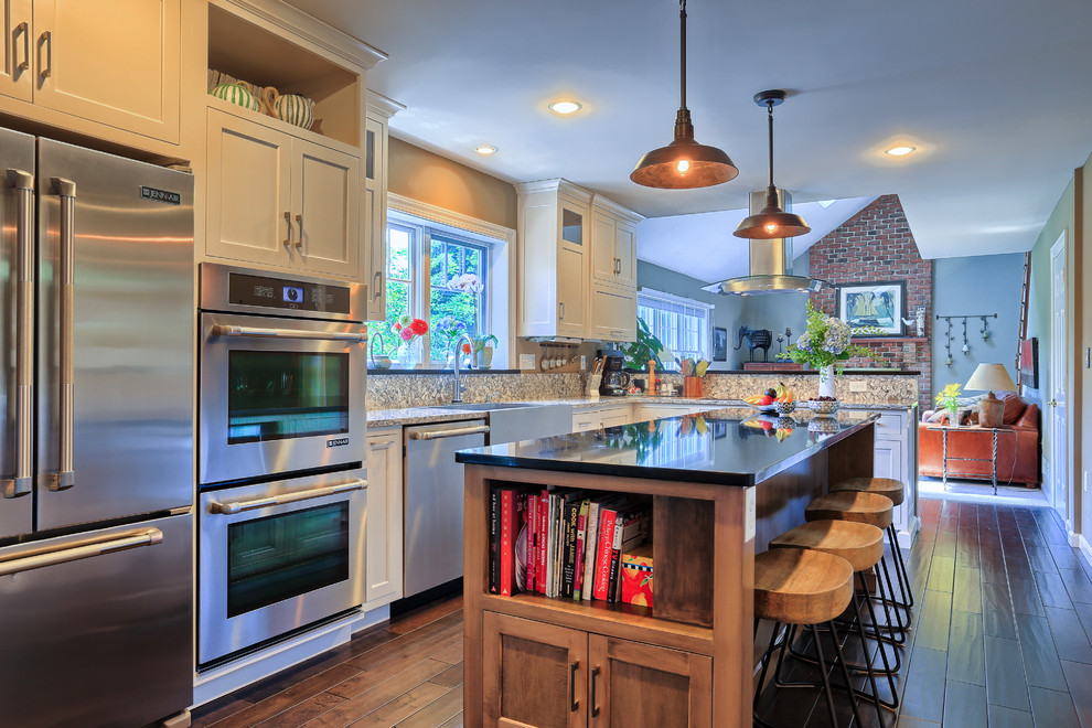 Shabby-Style Küche mit Landhausspüle, Küchengeräten aus Edelstahl, braunem Holzboden und Kücheninsel in Sonstige
