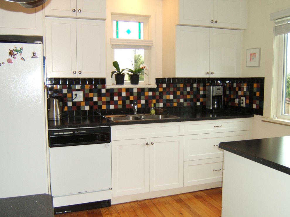 Design ideas for a small traditional single-wall enclosed kitchen in Vancouver with a built-in sink, shaker cabinets, white cabinets, granite worktops, multi-coloured splashback, mosaic tiled splashback, white appliances, medium hardwood flooring, a breakfast bar and brown floors.