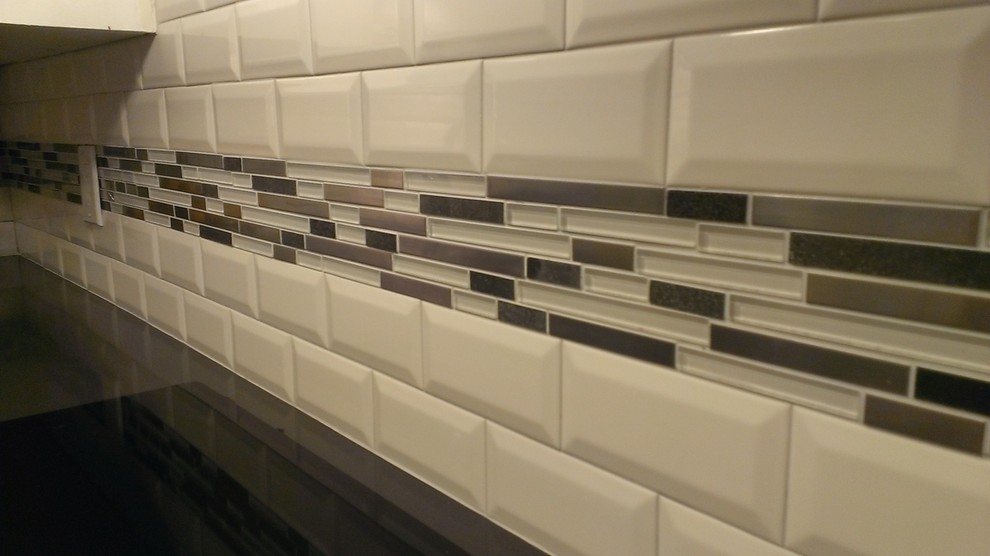 Bild på ett avskilt, mellanstort funkis l-kök, med släta luckor, vita skåp, bänkskiva i kvarts, vitt stänkskydd och stänkskydd i tunnelbanekakel