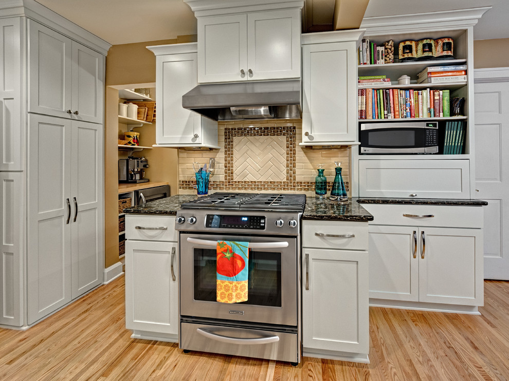 Klassische Küche mit Schrankfronten im Shaker-Stil, weißen Schränken, Küchenrückwand in Braun, Rückwand aus Metrofliesen und Küchengeräten aus Edelstahl in Minneapolis