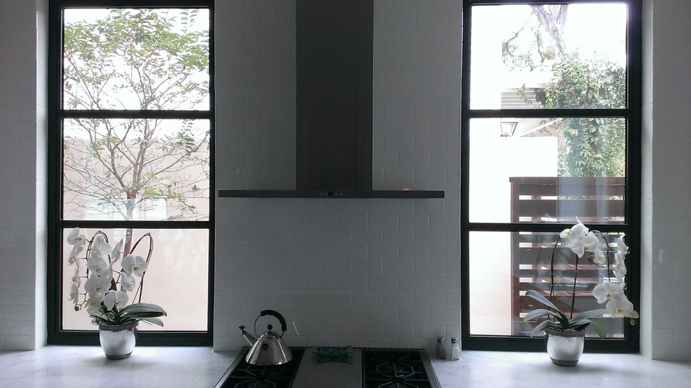 Minimalist u-shaped enclosed kitchen photo in Austin with an undermount sink, raised-panel cabinets, white cabinets, marble countertops, white backsplash, subway tile backsplash and stainless steel appliances