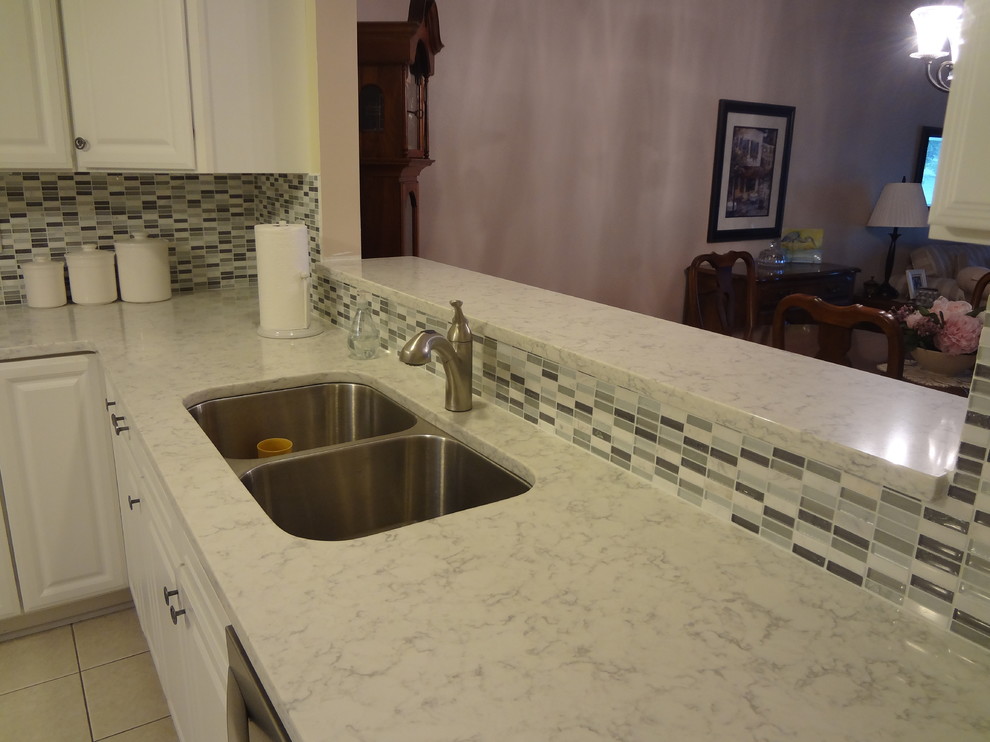 Inspiration for a small transitional l-shaped porcelain tile enclosed kitchen remodel in Chicago with an undermount sink, raised-panel cabinets, white cabinets, quartz countertops, gray backsplash, glass tile backsplash and stainless steel appliances