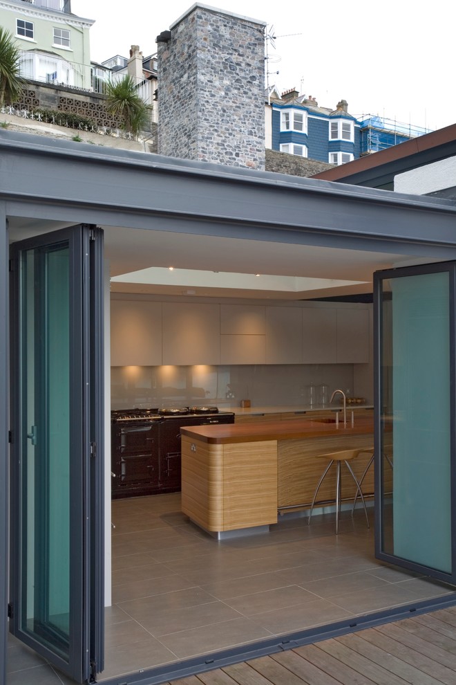 Inspiration pour une grande cuisine ouverte design en L et bois brun avec un placard à porte plane, un plan de travail en quartz modifié, une crédence verte et îlot.