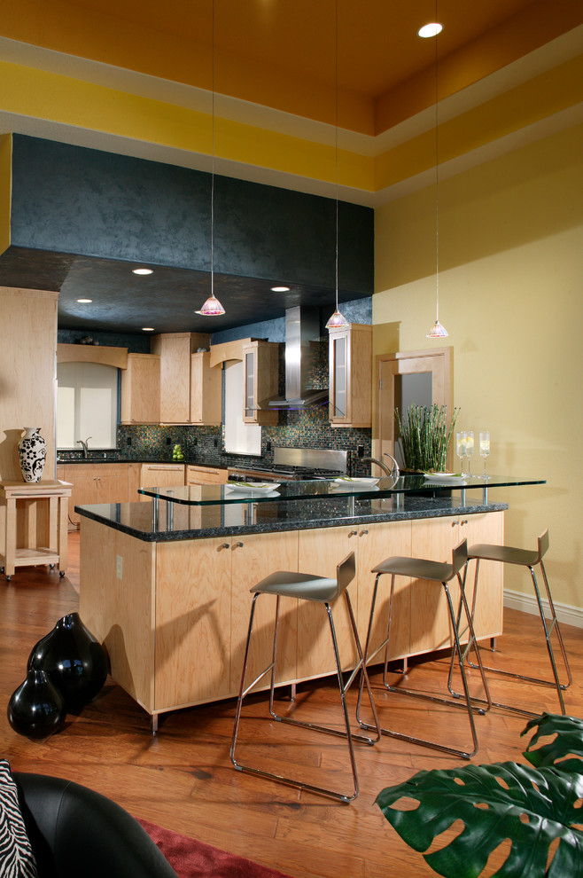 Cette image montre une cuisine minimaliste en bois clair de taille moyenne avec un placard à porte plane et un plan de travail en verre.
