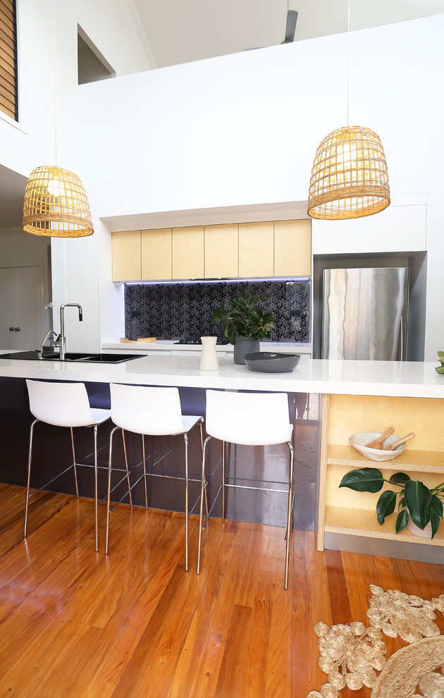 Zweizeilige Maritime Küche mit Einbauwaschbecken, Quarzwerkstein-Arbeitsplatte, Küchenrückwand in Grau, Glasrückwand, braunem Holzboden und Kücheninsel in Brisbane