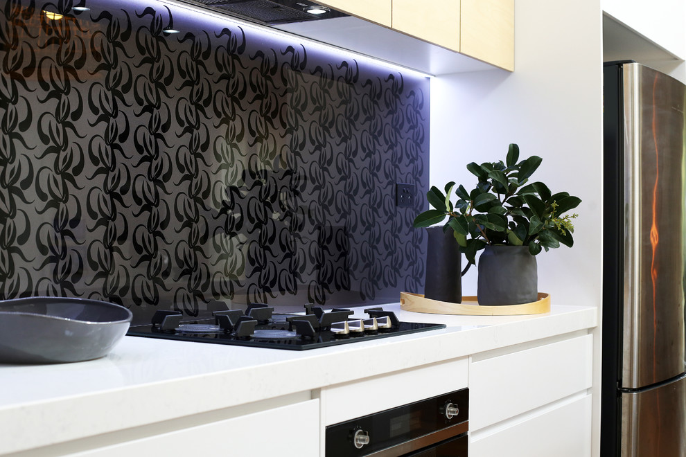Zweizeilige Maritime Küche mit Quarzwerkstein-Arbeitsplatte, Küchenrückwand in Grau, Glasrückwand und schwarzen Elektrogeräten in Brisbane