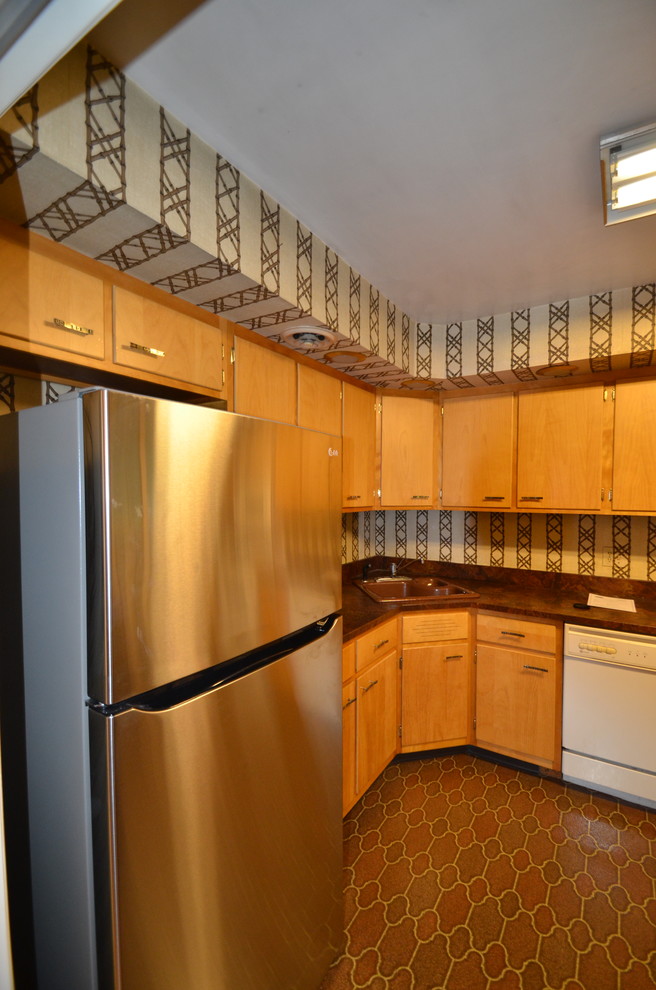 This is an example of a small traditional u-shaped enclosed kitchen in Philadelphia with flat-panel cabinets, light wood cabinets, white appliances, lino flooring and no island.