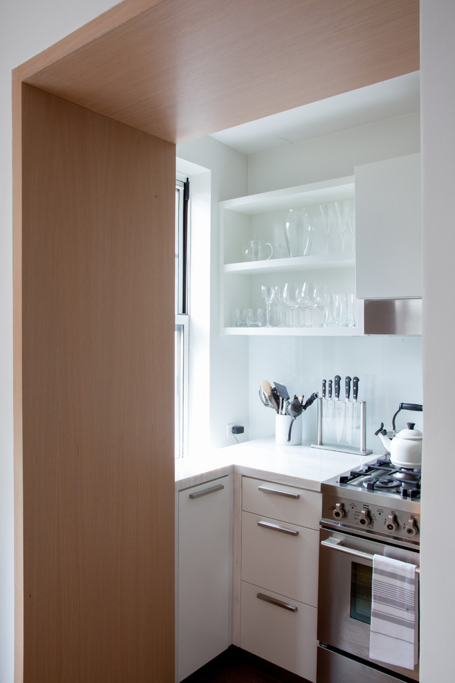 Imagen de cocina contemporánea cerrada con armarios abiertos, puertas de armario blancas, salpicadero blanco, salpicadero de vidrio templado y electrodomésticos de acero inoxidable