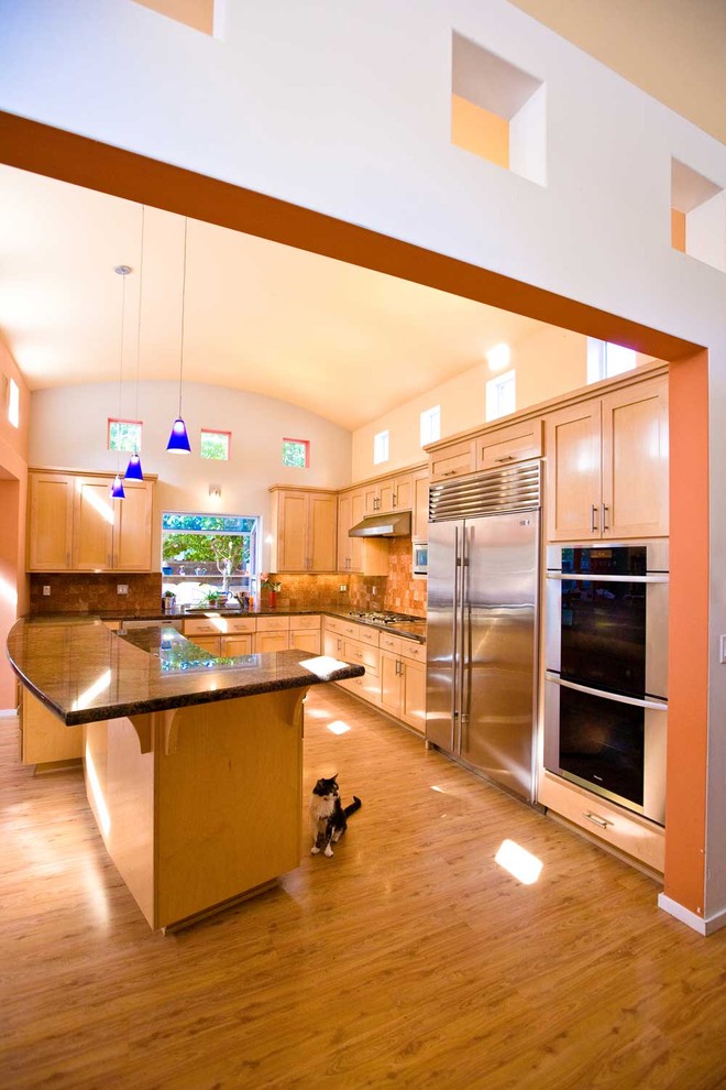 Foto på ett stort vintage brun l-kök, med skåp i shakerstil, rostfria vitvaror, en undermonterad diskho, skåp i ljust trä, granitbänkskiva, brunt stänkskydd, stänkskydd i stenkakel, mellanmörkt trägolv, en köksö och brunt golv