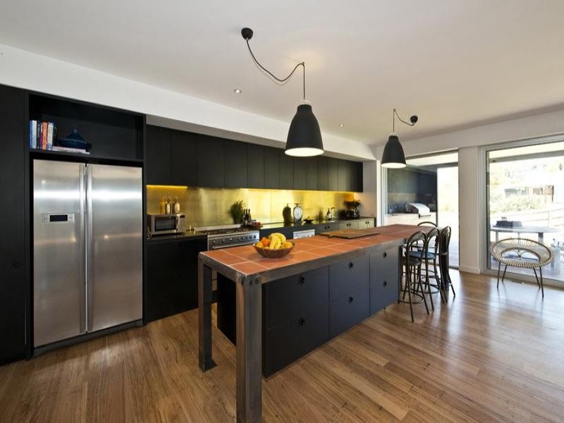 Photo of a large industrial single-wall open plan kitchen in Melbourne with tile countertops, metallic splashback and an island.