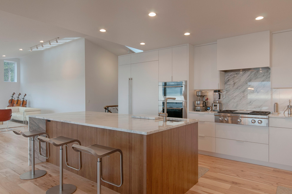 Foto de cocina comedor abovedada, isla de cocina pequeña y blanca y madera contemporánea grande con fregadero bajoencimera, armarios con paneles lisos, puertas de armario blancas, encimera de mármol, salpicadero blanco, salpicadero de mármol, electrodomésticos de acero inoxidable, suelo de madera clara, una isla, suelo beige y encimeras blancas