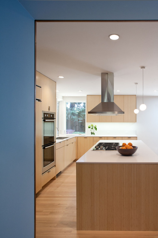 Cette image montre une cuisine ouverte minimaliste en L et bois brun avec un évier encastré, un placard à porte plane, un plan de travail en quartz modifié, une crédence blanche et un électroménager en acier inoxydable.