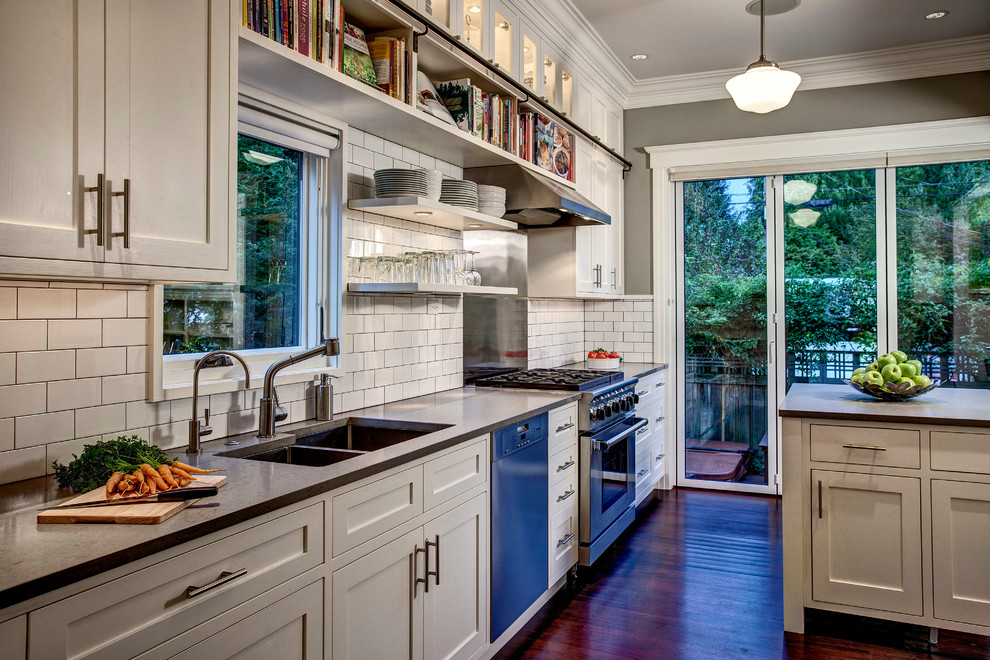 Exempel på ett amerikanskt linjärt kök, med en undermonterad diskho, vita skåp, vitt stänkskydd, stänkskydd i tunnelbanekakel, rostfria vitvaror, en köksö och skåp i shakerstil