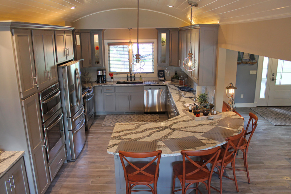 Idéer för att renovera ett mellanstort amerikanskt flerfärgad flerfärgat kök, med en undermonterad diskho, luckor med infälld panel, grå skåp, bänkskiva i kvarts, vitt stänkskydd, stänkskydd i keramik, rostfria vitvaror, mellanmörkt trägolv, en halv köksö och grått golv