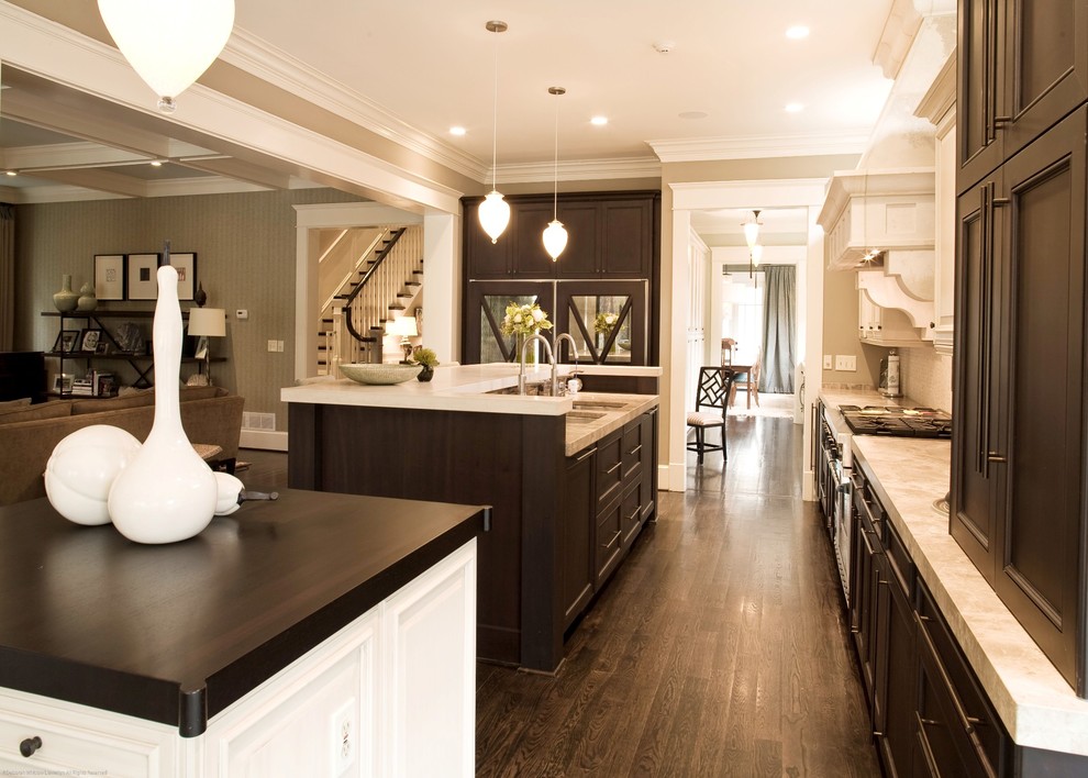 Large transitional galley medium tone wood floor open concept kitchen photo in Atlanta with recessed-panel cabinets, dark wood cabinets, stainless steel appliances and two islands