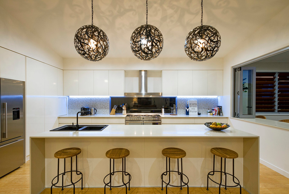 サンシャインコーストにあるコンテンポラリースタイルのおしゃれなアイランドキッチン (ドロップインシンク、フラットパネル扉のキャビネット、白いキャビネット、シルバーの調理設備) の写真