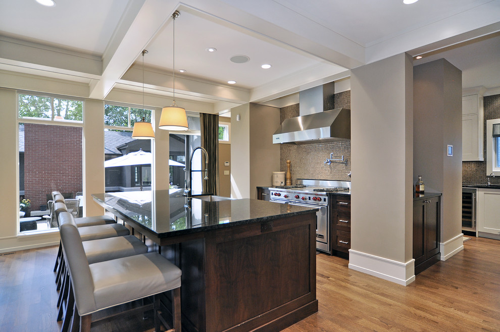 Transitional light wood floor kitchen photo in Calgary with stainless steel appliances, dark wood cabinets, granite countertops, metallic backsplash and mosaic tile backsplash