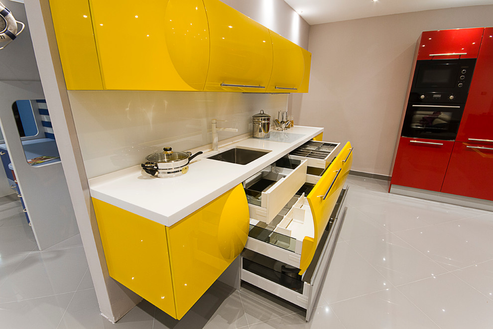 Idéer för mellanstora funkis kök, med en undermonterad diskho, gula skåp, bänkskiva i koppar, gult stänkskydd, glaspanel som stänkskydd, svarta vitvaror och klinkergolv i porslin