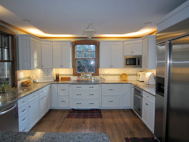 Moderne Wohnküche in U-Form mit Schrankfronten im Shaker-Stil, weißen Schränken, Granit-Arbeitsplatte, Rückwand aus Steinfliesen, Küchengeräten aus Edelstahl und braunem Holzboden in Chicago