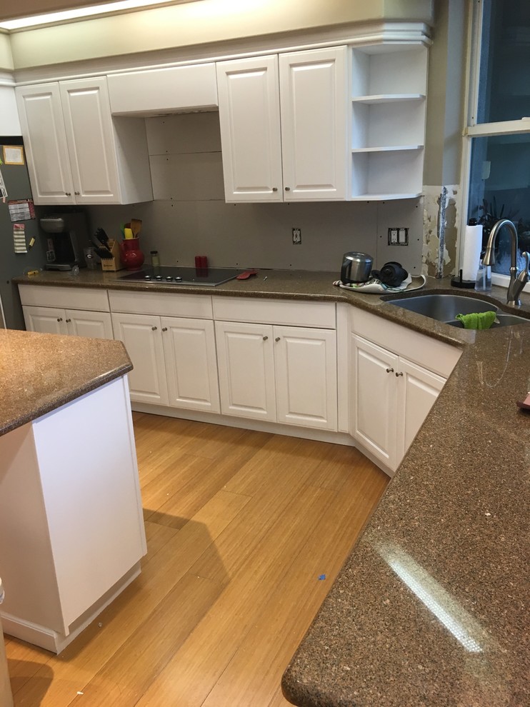 Design ideas for a medium sized classic single-wall open plan kitchen in Orlando with a double-bowl sink, raised-panel cabinets, white cabinets, granite worktops, stainless steel appliances, bamboo flooring, an island and brown floors.
