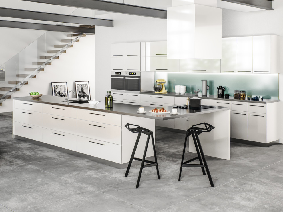 Inspiration for a large modern single-wall concrete floor eat-in kitchen remodel in Other with white cabinets, white backsplash, stainless steel appliances, an island, flat-panel cabinets, stainless steel countertops, glass sheet backsplash and an undermount sink