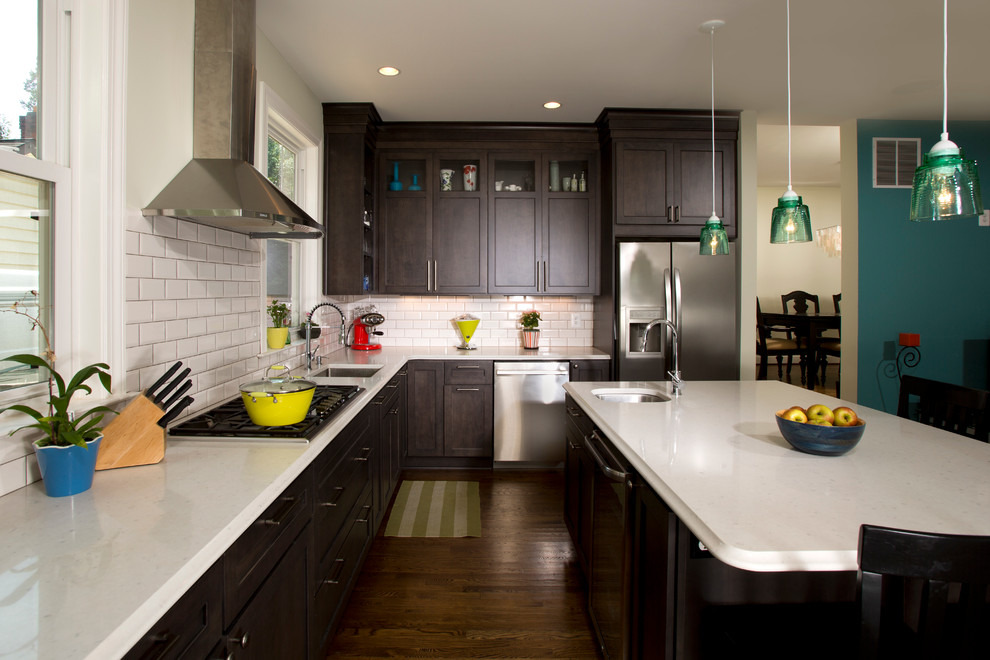 Mid-sized transitional l-shaped dark wood floor open concept kitchen photo in DC Metro with an undermount sink, beaded inset cabinets, dark wood cabinets, solid surface countertops, white backsplash, subway tile backsplash, stainless steel appliances and an island