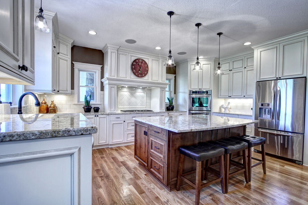 Foto på ett stort funkis kök, med släta luckor, vita skåp, granitbänkskiva, vitt stänkskydd, rostfria vitvaror, mellanmörkt trägolv och en köksö