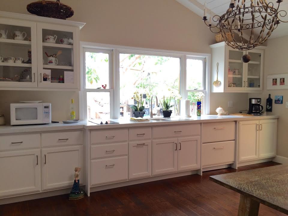 サンディエゴにある中くらいなトランジショナルスタイルのおしゃれなI型キッチン (落し込みパネル扉のキャビネット、白いキャビネット、パネルと同色の調理設備、無垢フローリング) の写真