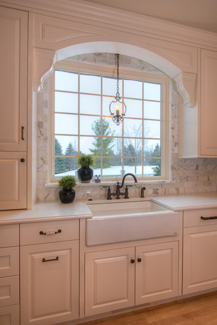 Bild på ett avskilt, stort vintage l-kök, med en rustik diskho, vita skåp, ljust trägolv, en köksö, luckor med profilerade fronter, granitbänkskiva, grått stänkskydd, vita vitvaror och stänkskydd i marmor