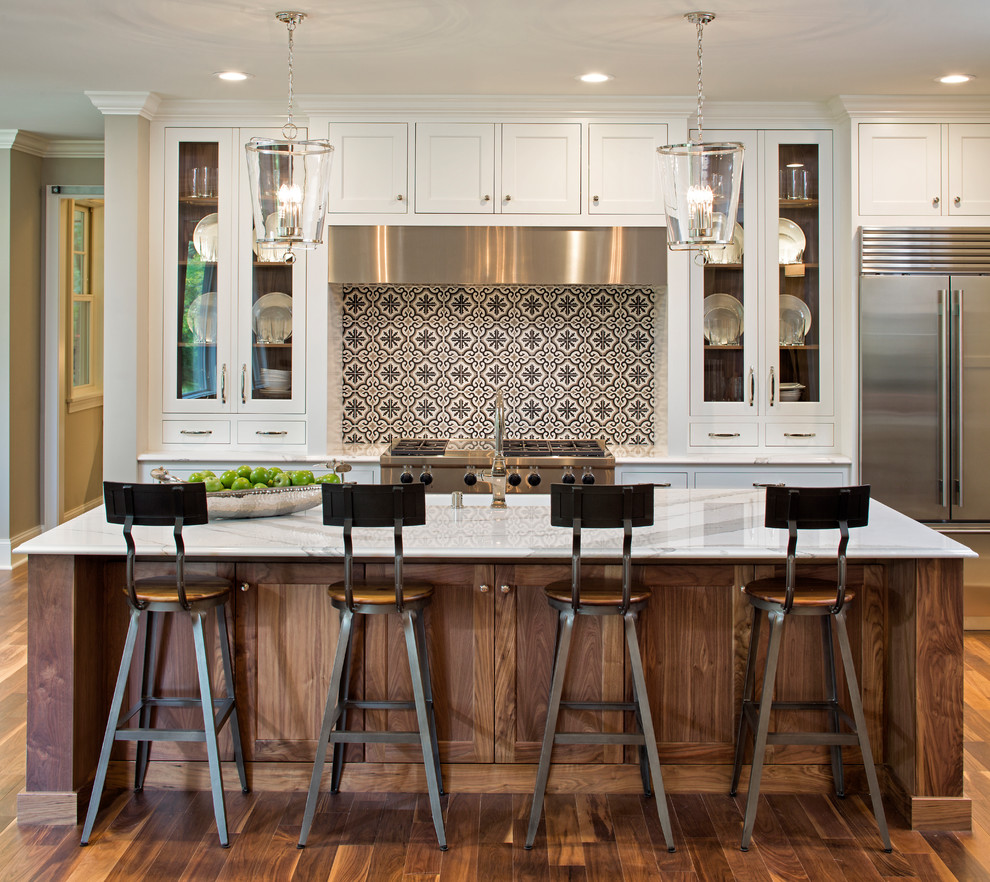 Photo of a traditional galley kitchen in Minneapolis with shaker cabinets, medium wood cabinets, multi-coloured splashback, stainless steel appliances, medium hardwood flooring, an island, brown floors and white worktops.