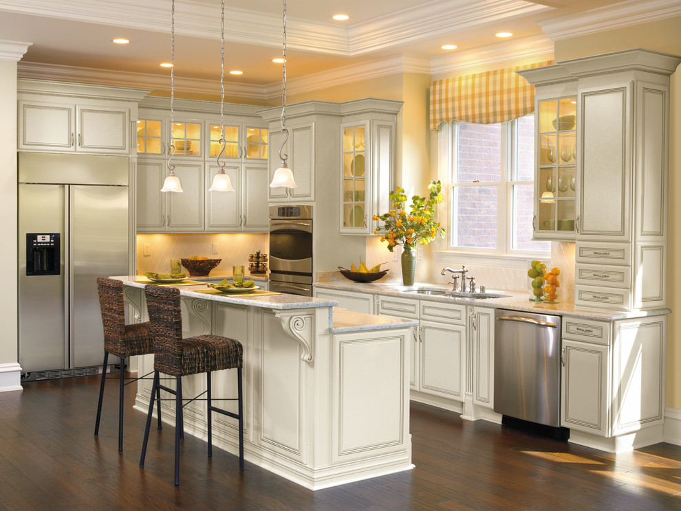 Example of a mid-sized transitional l-shaped dark wood floor and brown floor eat-in kitchen design in Other with a triple-bowl sink, raised-panel cabinets, white cabinets, quartz countertops, white backsplash, ceramic backsplash, stainless steel appliances and an island