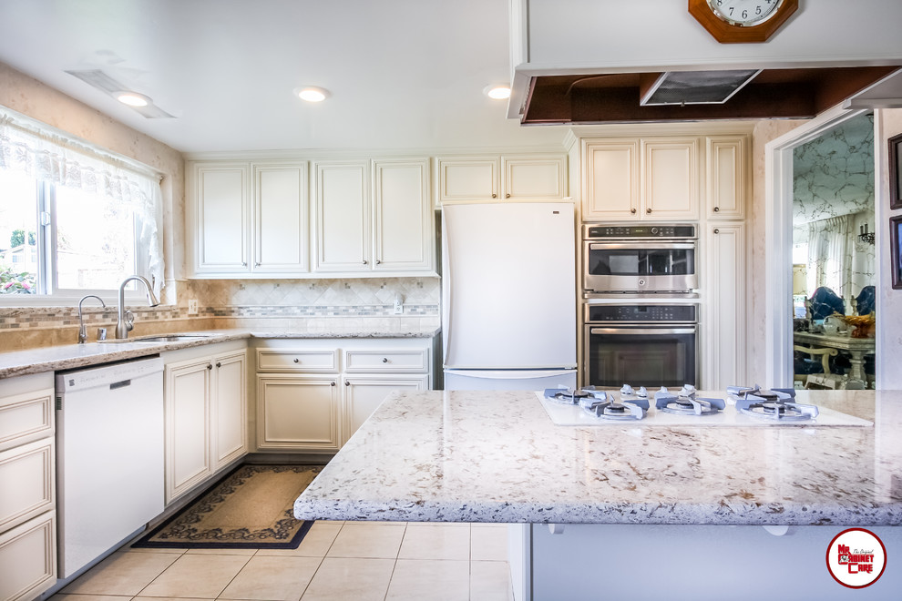 Foto på ett avskilt, mellanstort vintage l-kök, med en undermonterad diskho, luckor med upphöjd panel, vita skåp, bänkskiva i kvarts, flerfärgad stänkskydd, stänkskydd i stenkakel, vita vitvaror, klinkergolv i porslin och en köksö