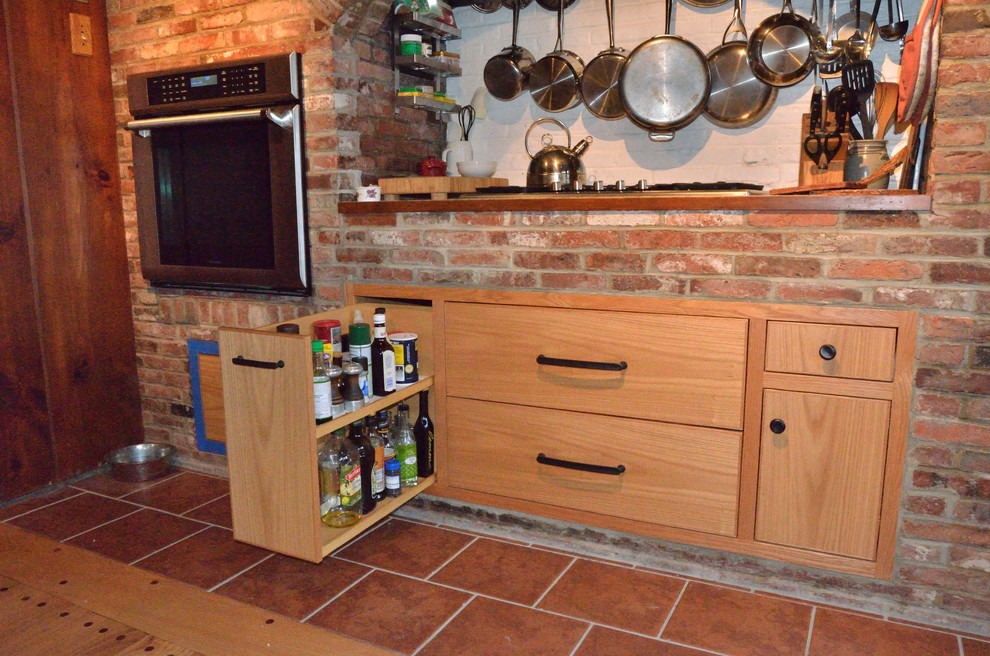 Cette image montre une cuisine américaine design en L et bois brun de taille moyenne avec un évier 3 bacs, un placard à porte plane, un plan de travail en granite, un électroménager en acier inoxydable et un sol en bois brun.